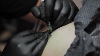 Profesyonel dövme sanatçısı bir adamın kolunda dövme yapar..