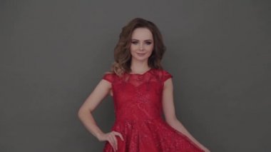 Gri arkaplanda poz veren kırmızı elbiseli güzel bir genç kız..