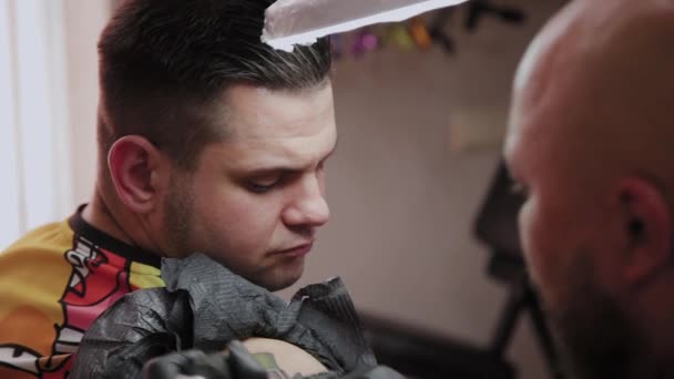 Професійний художник татуювання робить татуювання на руці чоловіка . — стокове відео