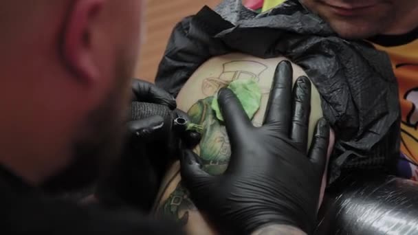 Professionell tatuerare gör en tatuering på en mans arm. — Stockvideo