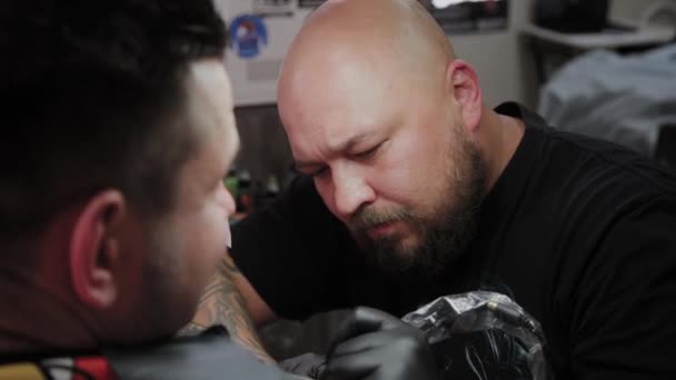 Professional tattoo artist makes a tattoo on a man s arm. — Stock Video