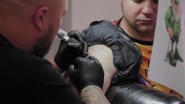 Professionell tatuerare gör en tatuering på en mans arm. — Stockvideo