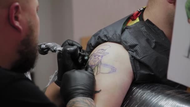 Tatoueur professionnel fait un tatouage sur le bras d'un homme . — Video