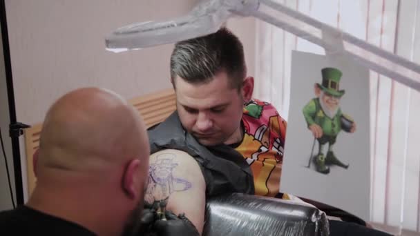 Professionell tatuerare gör en tatuering på en mans arm. — Stockvideo