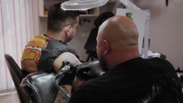 Profesionist tatuaj artist face un tatuaj pe brațul unui bărbat . — Videoclip de stoc