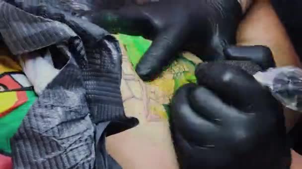 Профессиональный татуировщик делает татуировку на руке мужчины . — стоковое видео
