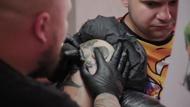 Professionell tatuerare gör en tatuering på en mans arm. — Stockvideo