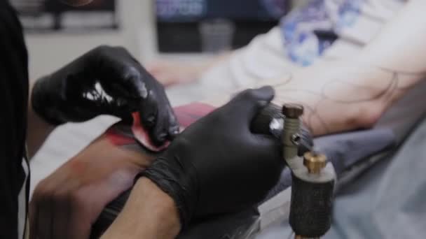 Professionell tatuerare gör en tatuering på en mans arm. — Stockvideo