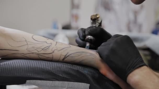 Professionell tatuerare gör en tatuering på en mans arm. — Stockvideo