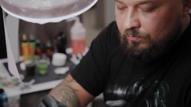 Επαγγελματίας καλλιτέχνης τατουάζ κάνει ένα τατουάζ στο χέρι ενός άνδρα. — Αρχείο Βίντεο