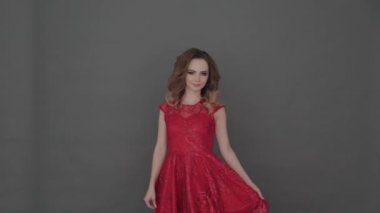Gri arkaplanda poz veren kırmızı elbiseli güzel bir genç kız..