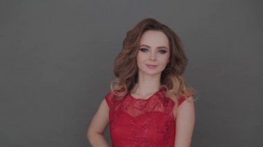 Gri arkaplanda poz veren kırmızı elbiseli güzel bir genç kız..
