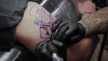 Profesyonel dövme sanatçısı bir adamın kolunda dövme yapar..