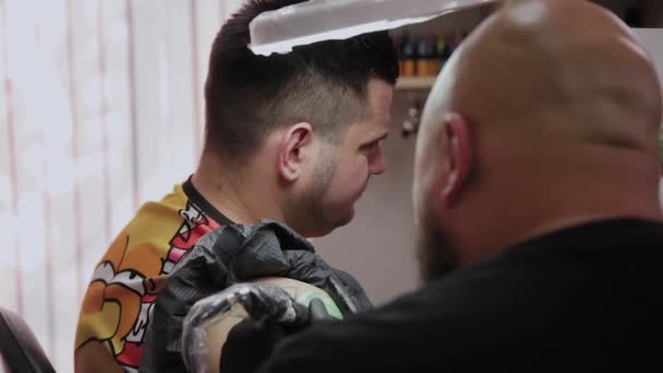 Professionele tattoo artiest maakt een tatoeage op de arm van een man. — Stockvideo