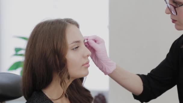 Make-up kunstenaar smelt de wenkbrauwen van de klant met gel voor de procedure. — Stockvideo