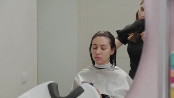 Friseurmädchen trocknet dem Kunden beim Friseur mit Haartrockner die Haare. — Stockvideo