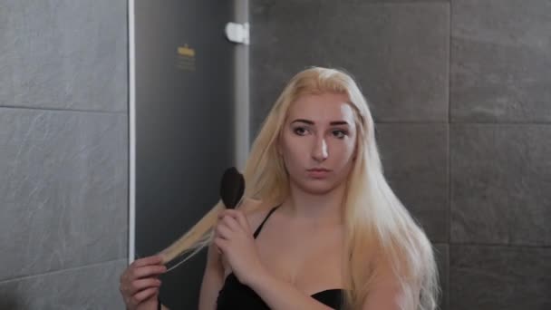 Menina bonita em um maiô penteando seu cabelo pelo espelho . — Vídeo de Stock