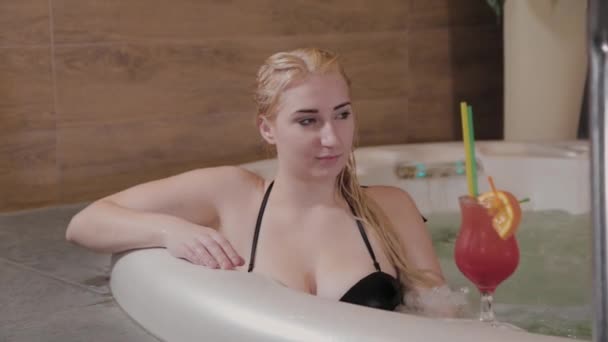 Vacker flicka med en cocktail i en jacuzzi. — Stockvideo