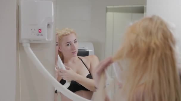 Schöne junge Mädchen trocknet Haare mit einem Haartrockner nach Wellness-Behandlungen. — Stockvideo