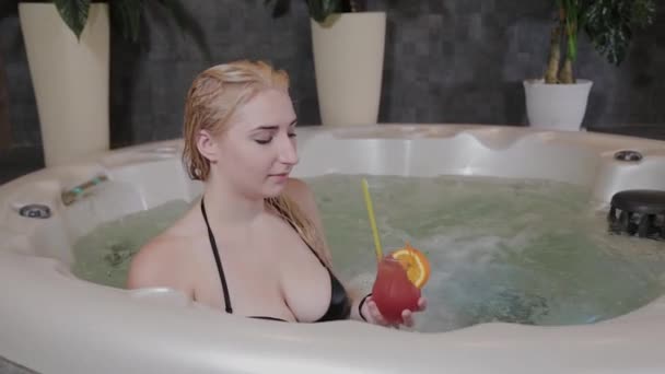 Schöne Mädchen mit einem Cocktail im Whirlpool. — Stockvideo