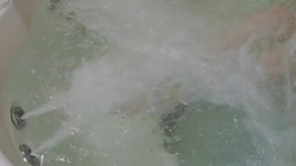 Schöne Beine eines jungen Mädchens unter dem Wasserstrom im Whirlpool. — Stockvideo