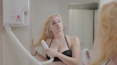 Güzel genç bir kız, kaplıca tedavisinden sonra saç kurutma makinesiyle saç kurutuyor..