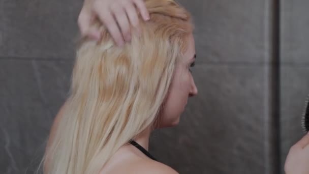 Красива дівчина в купальнику розчісує волосся біля дзеркала . — стокове відео