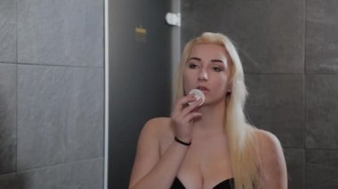 Mayo giymiş güzel bir kız aynada saçını tarıyor..