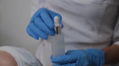 Profesyonel kozmetolojist hastaların yüzüne serum uygular.