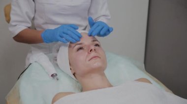 Profesyonel kozmetolojist güzellik salonunda yüz masajı yapıyor.