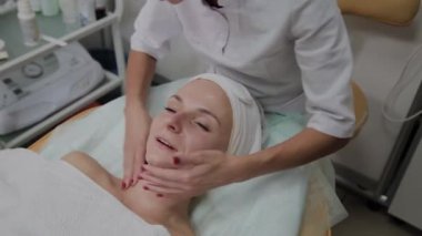 Profesyonel kozmetolojist kız yüzüne nemlendirici uygular.