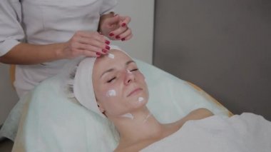 Profesyonel kozmetolojist güzellik salonunda yüz masajı yapıyor.