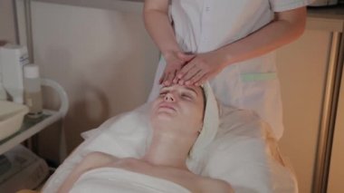 Profesyonel güzellik kozmetoloji ofisinde genç bir kız için karmaşık bir masaj yapar.