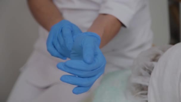 Ο επαγγελματίας κοσμητολόγος φοράει μπλε λαστιχένια γάντια για τη διαδικασία. — Αρχείο Βίντεο