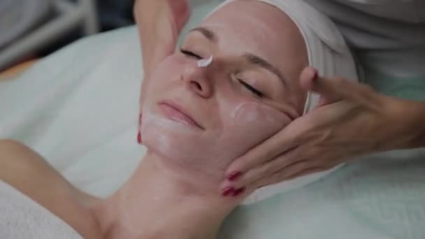 Cosmétologue professionnel faisant un massage du visage dans le salon de beauté . — Video