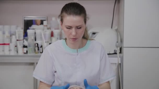 Cosmetologist feminino fazendo massagem facial a mulher idosa na clínica cosmetológica . — Vídeo de Stock