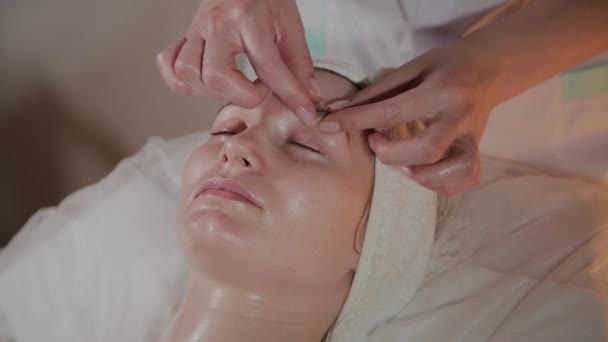 Professionele schoonheidsspecialiste maakt een complexe massage aan een jong meisje in het cosmetologie kantoor. — Stockvideo