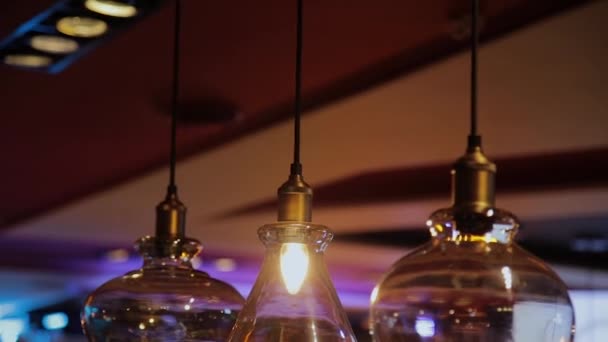 밤에 카페에서 어두운 배경에 매달려 빈티지와 복고풍 노란색 전구. 비스트로와 레스토랑에서 많은 고급 조명 램프 장식 산업 로프트 스타일. — 비디오