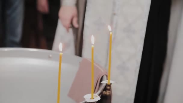 Fonts pour le baptême des bébés avec des bougies allumées dans l'Église orthodoxe . — Video