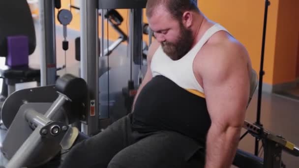 Sehr großer bärtiger Bodybuilder trainiert Beine im Fitnessstudio. — Stockvideo
