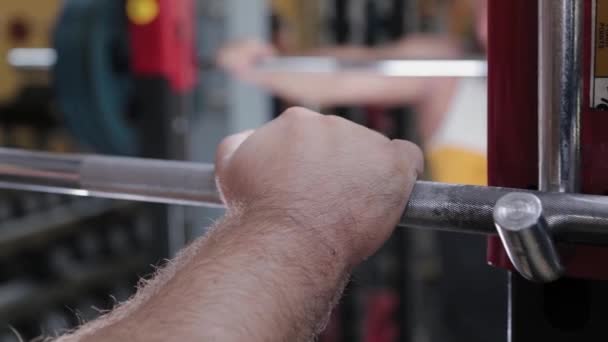 Een grote en krachtige gewichtheffer neemt de lange halter met zijn hand. — Stockvideo