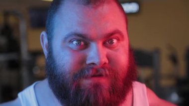 Neon ışığı altında kötü sakallı bir adamın kocaman yüzü..