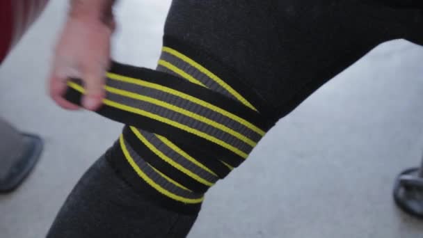 Büyük ve güçlü halterci dizlerine elastik sert bandajlar sarar.. — Stok video