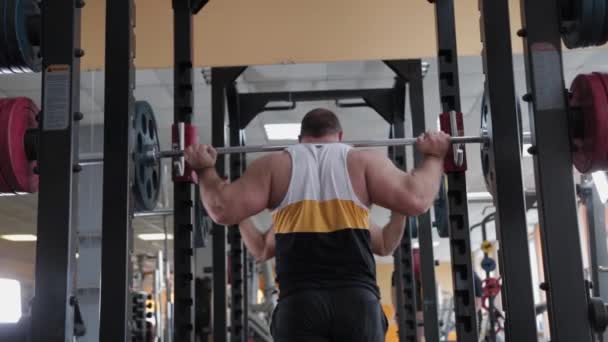 Grote en krachtige gewichtheffer hurkt met een zware lange halter. — Stockvideo