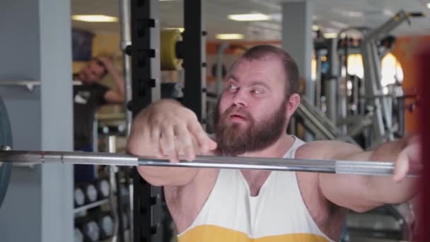 Un levantador de pesas grande y poderoso muerde la barra airadamente antes de hacer el ejercicio . — Vídeo de stock