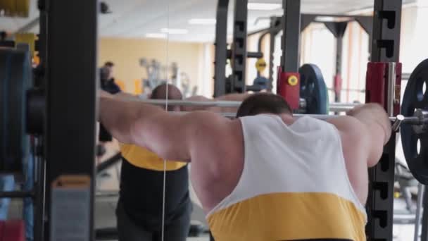 Um levantador de peso grande e poderoso está se preparando para agachar com uma barra . — Vídeo de Stock