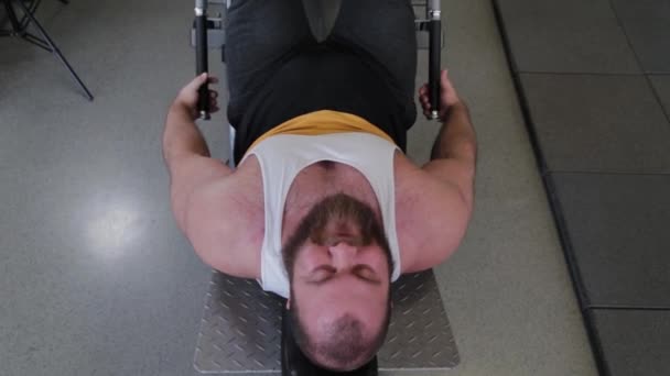 Großer und leistungsstarker Gewichtheber trainiert Beine am Simulator im Fitnessstudio.
