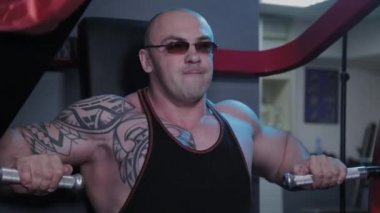 Profesyonel vücut geliştirici bir spor kulübünde simülatörde göğüs kaslarını çalıştırır..