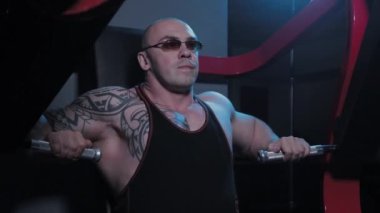 Profesyonel vücut geliştirici bir spor kulübünde simülatörde göğüs kaslarını çalıştırır..