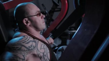 Profesyonel vücut geliştirici bir spor kulübünde simülatörde göğüs kaslarını çalıştırır..